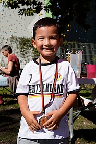 Ein kleiner Junge mit einer Medaille strahlt in die Kamera