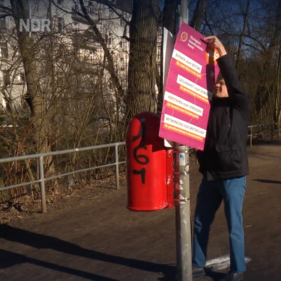 Spitzenkandidat hängt ein Plakat an einem Mast auf